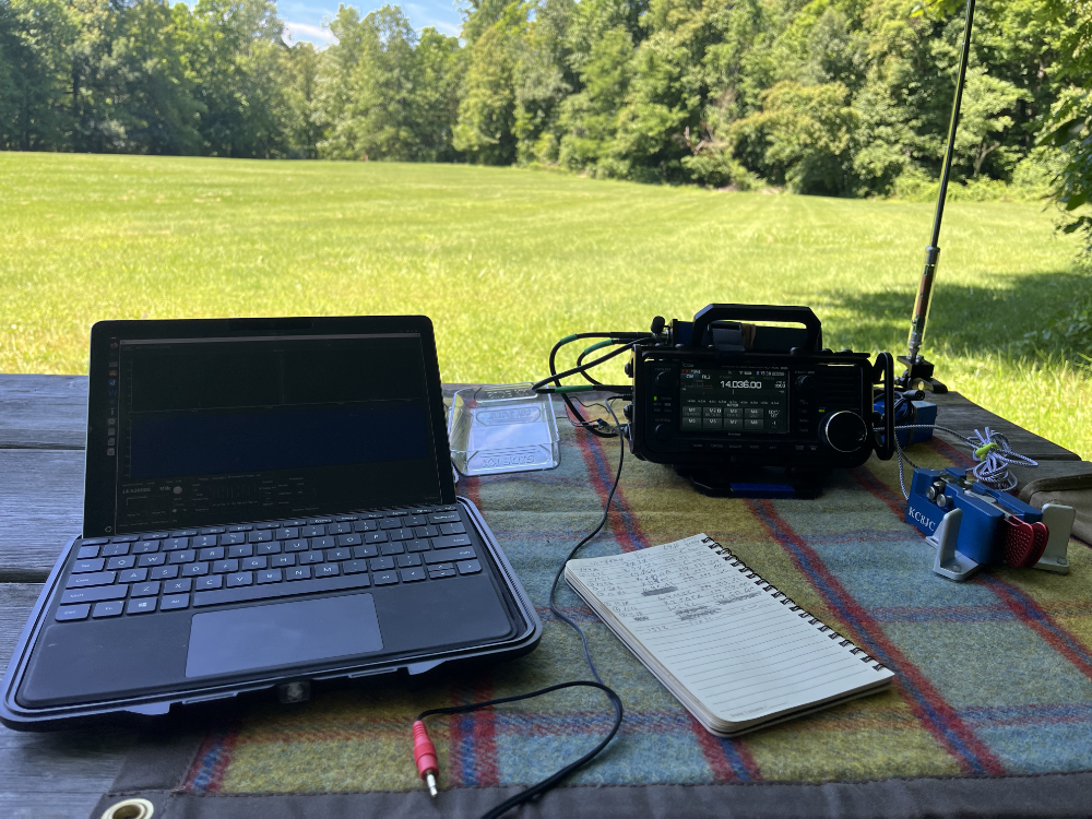 MS Surface GO 2, IC-705, log book and paddles on a tarp with the AX1 antenna in the background.