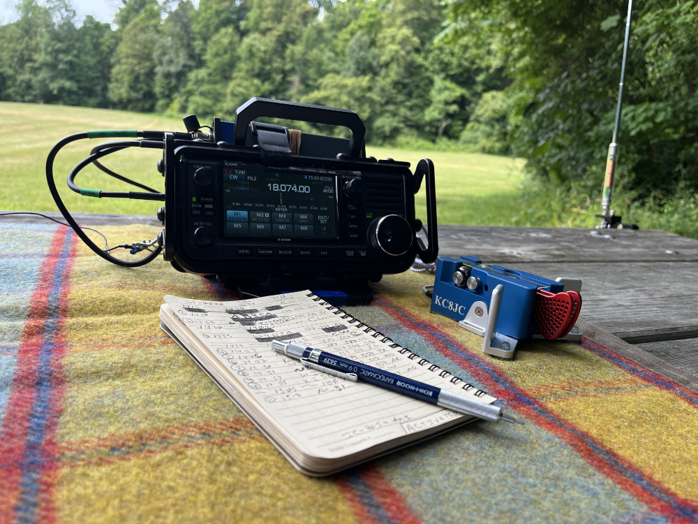 IC-705, Begali Traveler, and log book on a tarp.